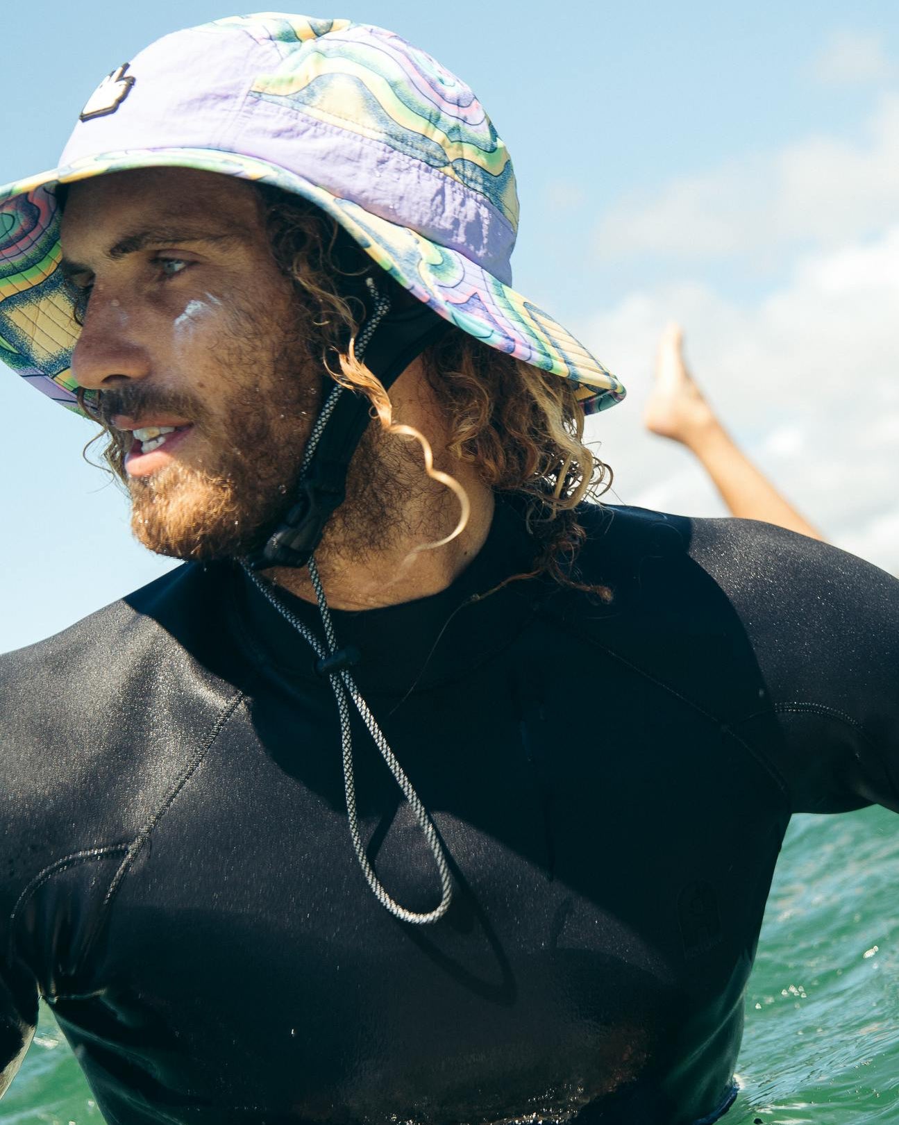 Person wearing a wetsuit and colorful hat in the ocean